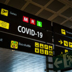 Information panel with Covid-19 word on it at an international airport.