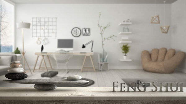 Wooden vintage table shelf with stone balance and 3d letters making the word feng shui over modern home corner office, zen concept interior design